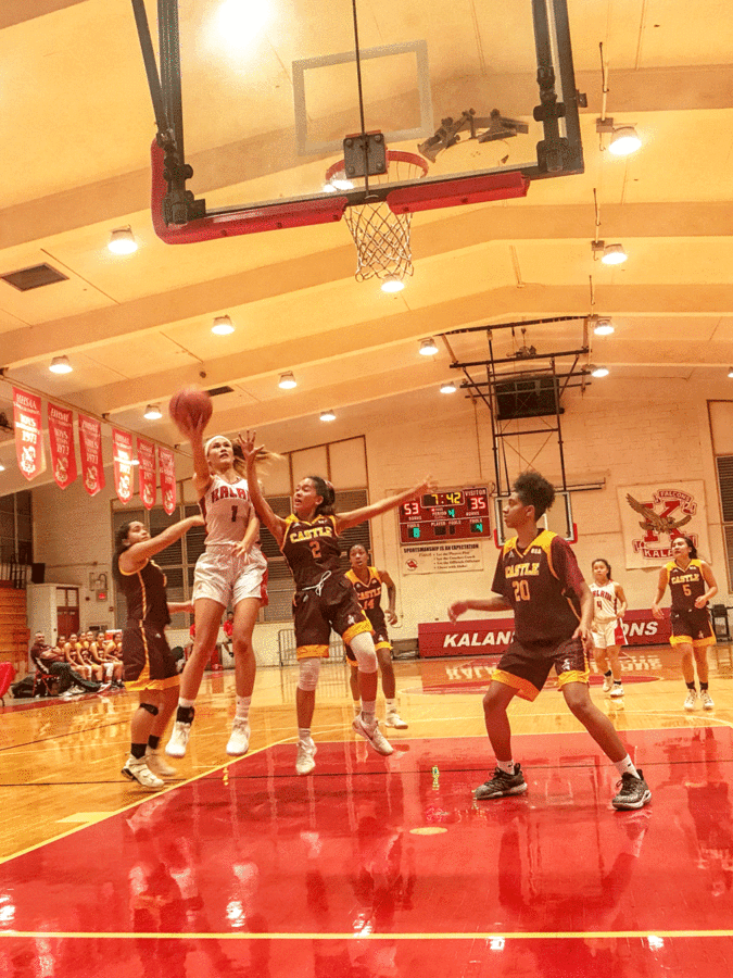 Kamalu Kamakawiwaole (12) drives to the basket in the final minutes of the fourth quarter in the Lady Falcons game against Castle on Dec. 12 at Kalani High School. The Falcons won 75-47 in a hard-fought game against the Knights. Kamakawiwaole led with 19 points, followed by Kalena Halunajan (10) with 17 and Heidi Kishaba (12) with 13 points. It was a physical game between the two schools. Kalani got into foul trouble early in the 2nd quarter but ended up winning by 28 points. Photo by Serena Wong 2018. 