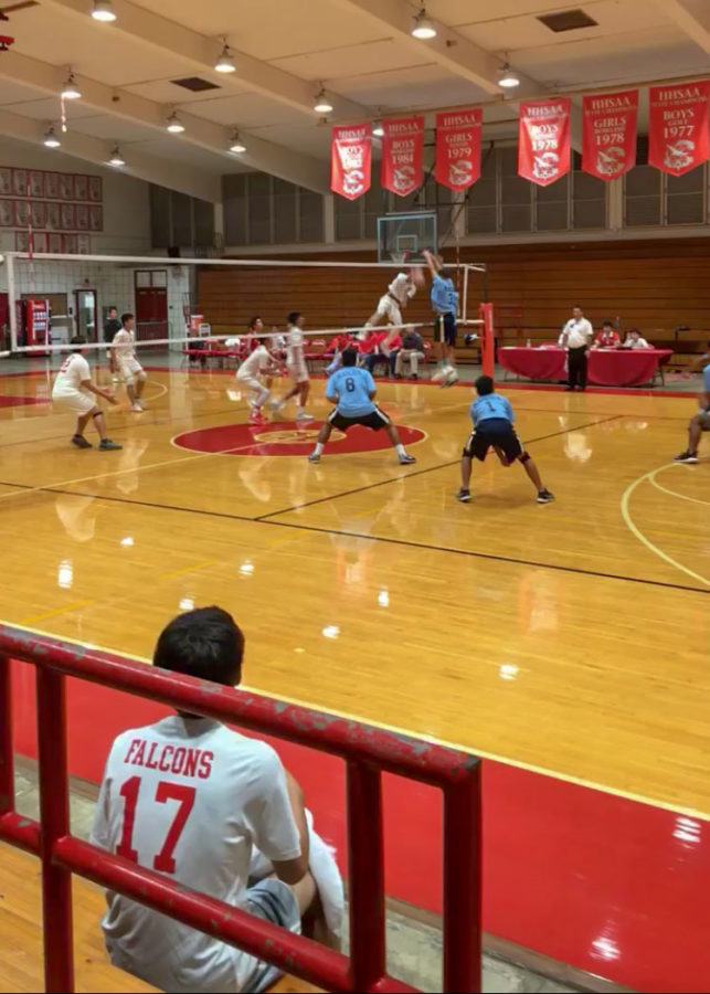 Kalanis JV volleyball team watches from the bleachers as Senior Keoni Thiim spikes a ball against Kailua in Varsitys season opener. Photo by Serena Wong 2019. 