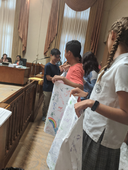 Over 15 students from across the island showed up at Honolulu Hale on Nov.14 to support Bill 40. The students gathered hundreds of signatures from classmates to create the over 60-foot-long document they refer to as “The Scroll” and presented it at the hearing. Wilson Tran, a Junior at Kalani High School and head of Kalani’s Green Team believes the students efforts were successful. “It was more than just that, and the poster exemplified this, he said. It was a showing of powerful youth support and just how much influence people can have in large numbers. It was a check on our city officials for one thing, but in the bigger picture it was saying that we want a future.” Photo by Lucy Fagan 2019. 