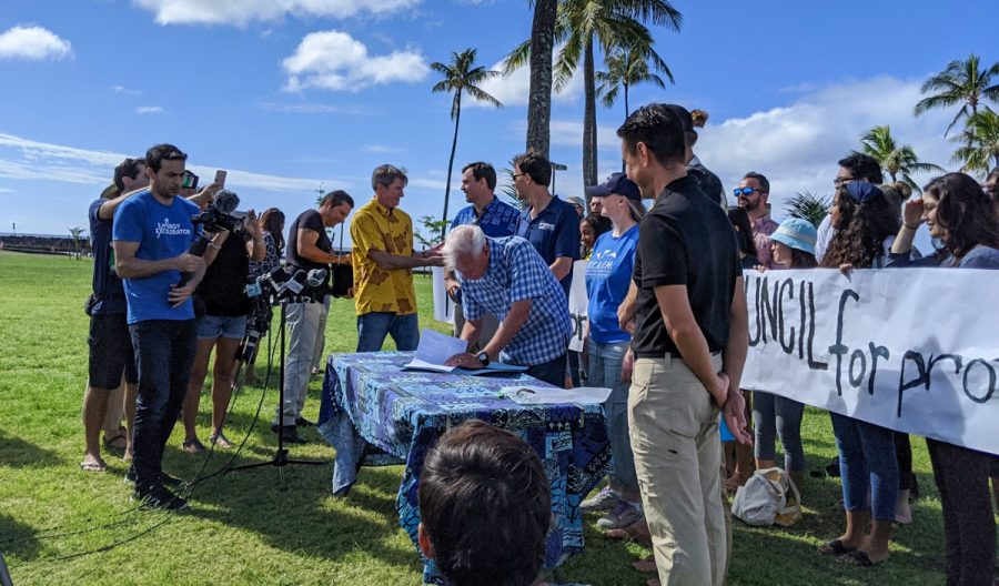 Mayor Kirk Caldwell signs Bill 40 into law on Dec. 15 at 11 a.m. at Magic Island. By signing the Bill I believe there is hope for the future, Caldwell shared. Bill 40 is a landmark piece of legislation to ban single-use plastics. Many were gathered to witness the event. Photo by Lucy Fagan 2019. 