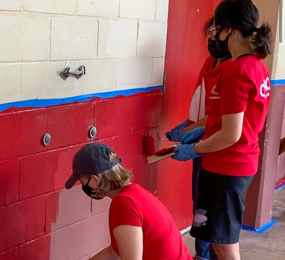 Kaydee Leong (right) and Olivia Kulaga (left) repaint one of the C-buildings walls for the Key Club campus beautification volunteer event. Photo by Ms.Takayesu. 