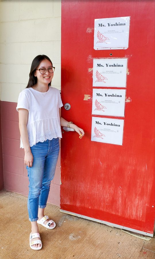 Miss Yoshina stands beside her classroom door, which displays all of her academic degrees. Photo by Ranson Silva. 