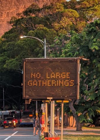 An electronic road sign spreads the message of Covid-19, cautioning “No large gatherings”  at the intersection of Kalakaua and Monsarrat Avenues. The sign reminds people not to have large gatherings. It alternates through three other messages: “Stop the spread,” “Do your part,” and “Violators will be cited.” During the Covid-19 pandemic, social gatherings on Oahu have been limited to 10 people indoors and 25 people outdoors. According to KHON 2, Honolulu Mayor Rick Blangiardi extended the suspension of large gatherings. The suspension started on Sept. 22, but Blangiardi extended it until Oct. 19. To stay safe, and prevent the risk of case spikes, remember to avoid large gatherings. Photo by Eleni Cheng 2021.