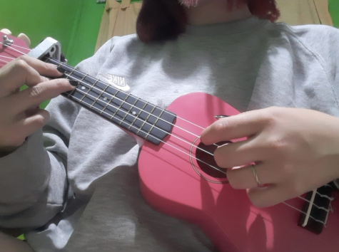 A student plays a pink ukelele. 